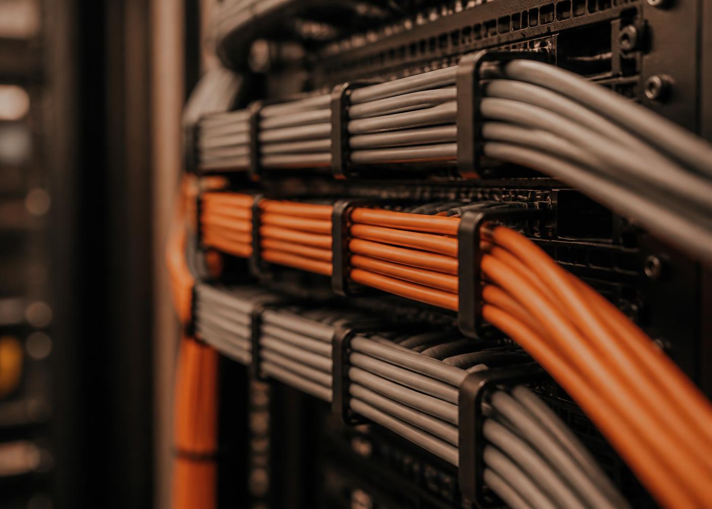 Close-up of neatly bundled grey and orange network patch cables in a server rack
